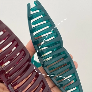 Close-up of large jelly-textured hair claws in deep red and dark green resin