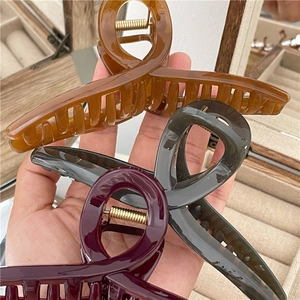 Close-up of large resin hair claws in amber, gray and burgundy with strong gold springs