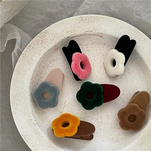 Flat lay of six colorful flocked flower hair clips on a textured stone tray
