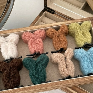 Detailed view of eight colorful plush animal ear hair claws in a wooden display box