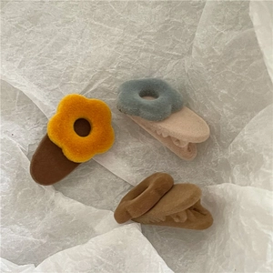 Detailed view of flocked floral duckbill hair clips with a matte velvety finish