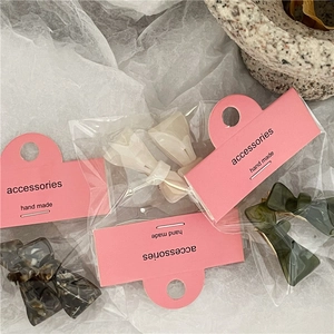 Close-up of tortoise shell and green acetate mini hair clips in individual packaging