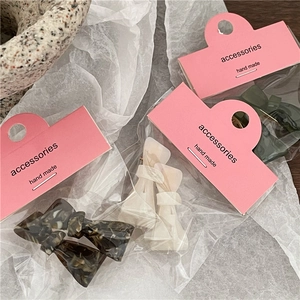 Three acetate bow hair clips in tortoiseshell, cream and green on card packaging