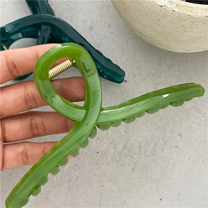 Detail of high-gloss translucent resin hair claw clips in olive and dark green colors