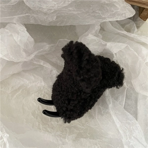Close-up of a black faux lamb wool hair claw clip with warm teddy fur texture