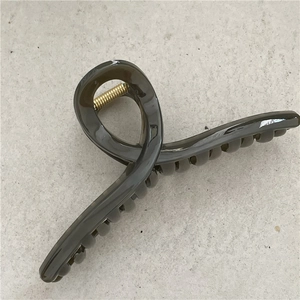 Macro shot of large translucent grey hair claw clip showing shiny texture and metal spring
