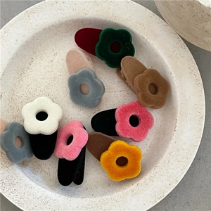 Close-up of colorful flocked flower hair clips with soft velvet texture on a tray