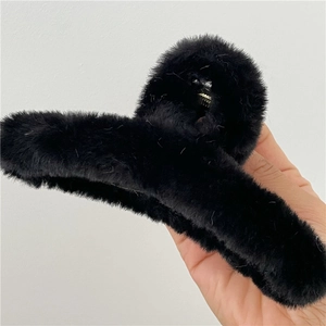 Détail d'une pince à cheveux noire en peluche avec un ressort métallique doré robuste