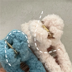 Detailed close-up of fluffy pink and blue lamb wool hair claws with golden metal springs