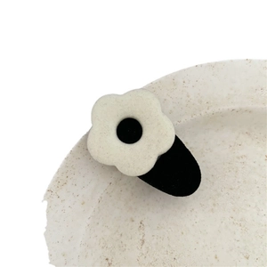 Cute black and white flocked flower hair clip on a minimalist white ceramic plate