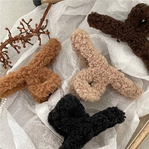 Close-up of fluffy faux shearling hair claws in brown, beige, and black on a textured base