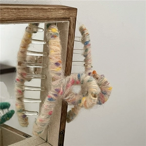 Détail macro d'une pince à cheveux en laine colorée montrant la texture douce