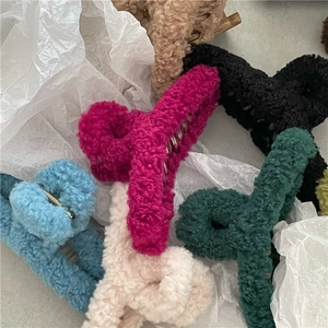 Flat lay of colorful plush faux fur hair claw clips on white paper background