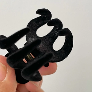 Dettaglio mini molletta per capelli nera floccata con trama in velluto e molla in metallo