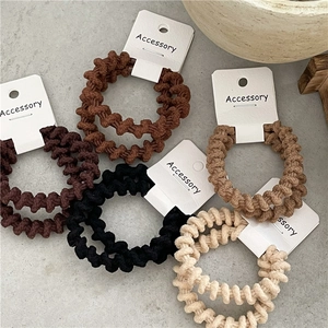 Set di cinque elastici per capelli a costine nei toni terra, marrone e beige su carta
