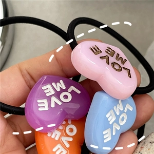 Close-up of colorful heart resin hair ties with LOVE ME text and black elastic bands