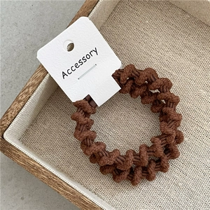 Dettaglio di elastici per capelli a spirale marroni spessi su carta in vassoio legno