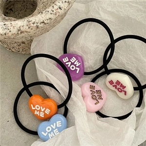 Close-up of colorful heart-shaped hair ties featuring LOVE ME lettering and elastic bands