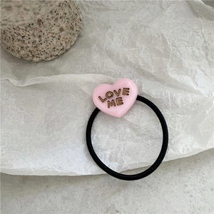Detail of pink heart hair tie with LOVE ME text on high-elasticity black rubber band