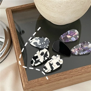 Close-up detail of acetate water drop hair clips with marble patterns and glossy finish