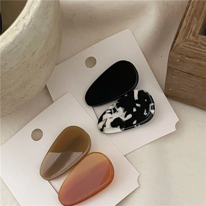 Detailed view of four acetate teardrop hair clips in marble and amber colors on card