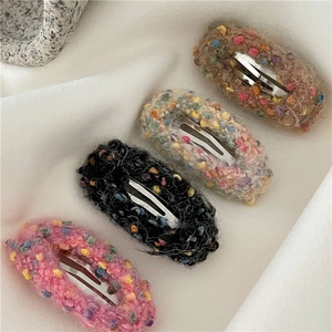 Macro detail of textured tweed donut hair clips with colorful fiber balls and metal clips