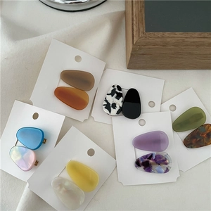 Flat lay of colorful acetic acid teardrop hair clips set on elegant white fabric
