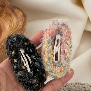 Close-up of handmade knitted plush donut hair clips with colorful yarn texture and silver metal base