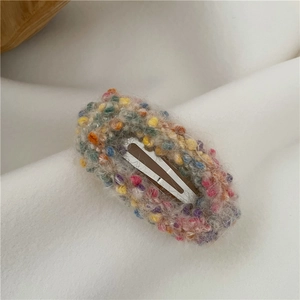 Close-up of donut-style colorful plush BB hair clip with textured knit fabric
