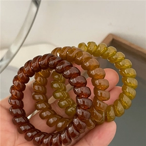 Three-pack spiral jelly hair ties in brown, amber, and olive green for elegant styling