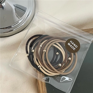Dettaglio del set di 10 elastici per capelli dai toni terra con perline oro e borsa fatta a mano