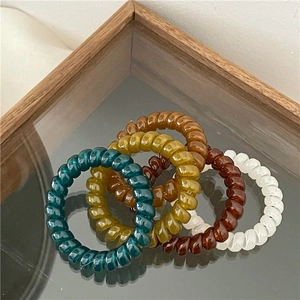 Elastic spiral telephone wire hair ties in dark green, amber, and reddish brown colors