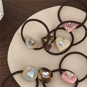 Detailed view of luxury acetate heart hair ties with crystals on stone tray
