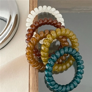 Close-up of four jelly-textured spiral hair ties in retro autumn earth tone colors