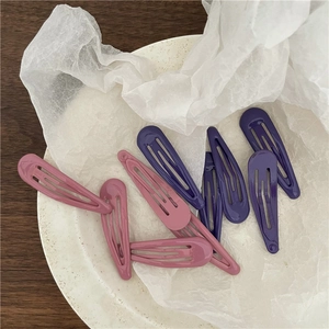 Dettaglio delle mollette per capelli in metallo opaco rosa e viola a goccia
