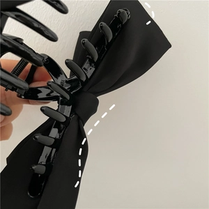 Detailed close-up showing the strong metal spring and teeth of the black velvet bow hair claw