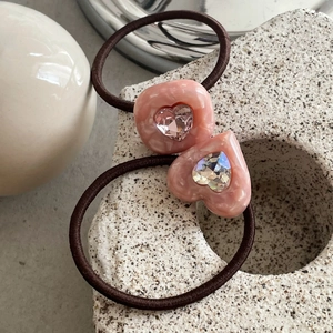 Detailed macro view of hair tie featuring a pink marble heart and a sparkling faceted crystal