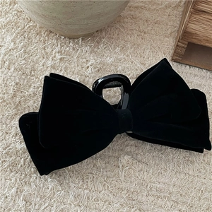 Detailed close-up of premium black velvet bow hair claw clip with elegant fabric texture