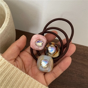 Three-piece acetate hair ties with heart crystals and marble texture pattern on brown elastic