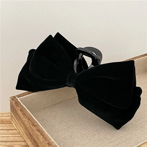 Close-up of elegant black velvet bow hair claw clip showing detailed soft fabric texture