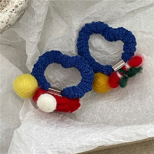 Détail de l'élastique à cheveux en laine feutrée bleue avec des pompons colorés