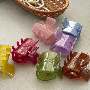 Colorful acetate bow hair clips in jelly colors for women on a rustic textured background