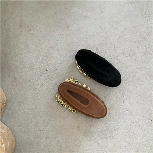 Détail de barrettes ovales en velours noir et marron avec bordure dorée chic