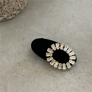 Vue détaillée de la pince à cheveux ovale dorée avec zircons sur un support en velours