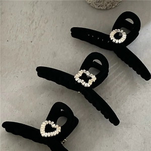 Détail de pinces à cheveux floquées noires avec zircons scintillants en forme de cœur