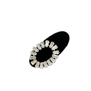 Pince à cheveux ovale dorée élégante avec zircons baguette sur support noir