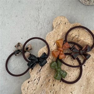 Flat lay of acetate bow hair ties in multiple colors on a travertine display stand