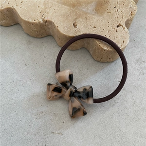 Detail of elegant acetate bow hair tie with tortoiseshell texture on stone background