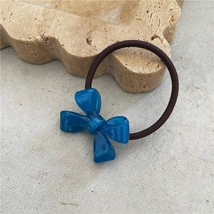 Detailed shot of dark blue acetate bow hair tie with elastic band on stone texture