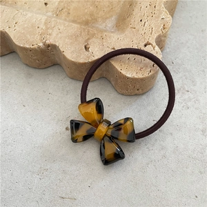 Close-up of amber tortoiseshell acetate bow hair tie on a decorative stone tray